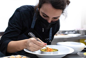 Student detailing a culinary creation with tweezers at the Culinary Institute of Barcelona.